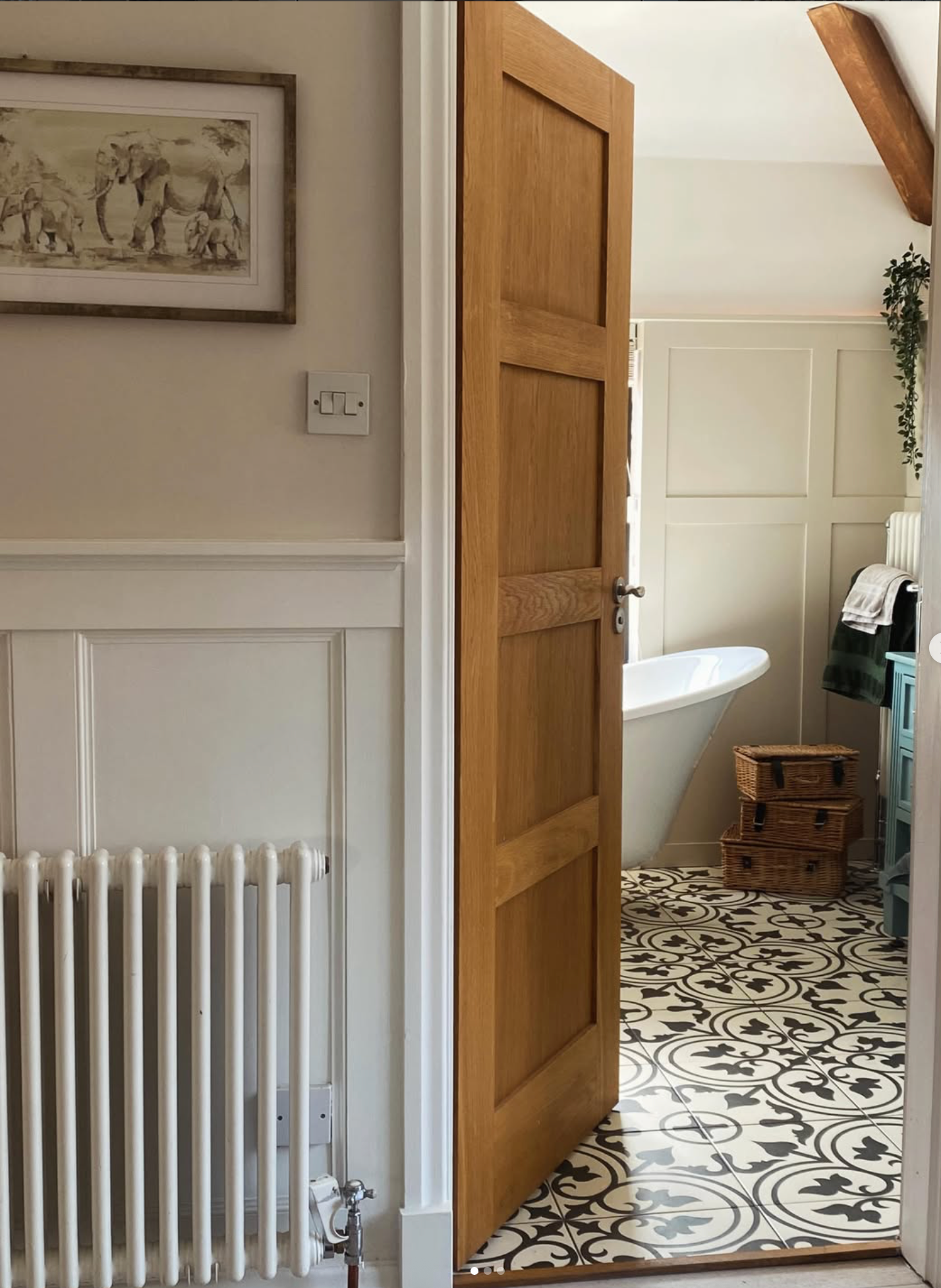 Oak panel door opening onto a bespoke bathroom with patterned tile floor