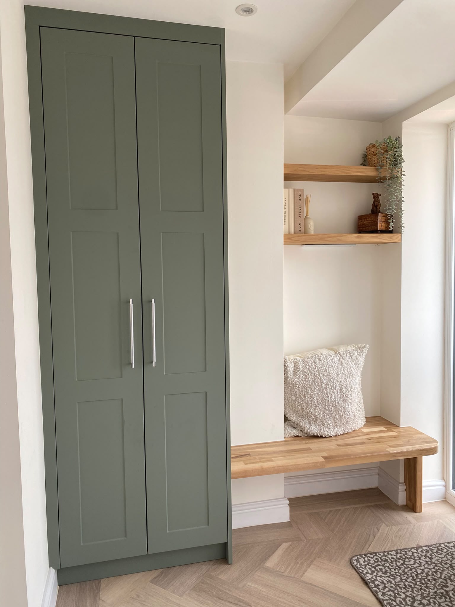 Olive green fitted wardrobe beside a window nook
