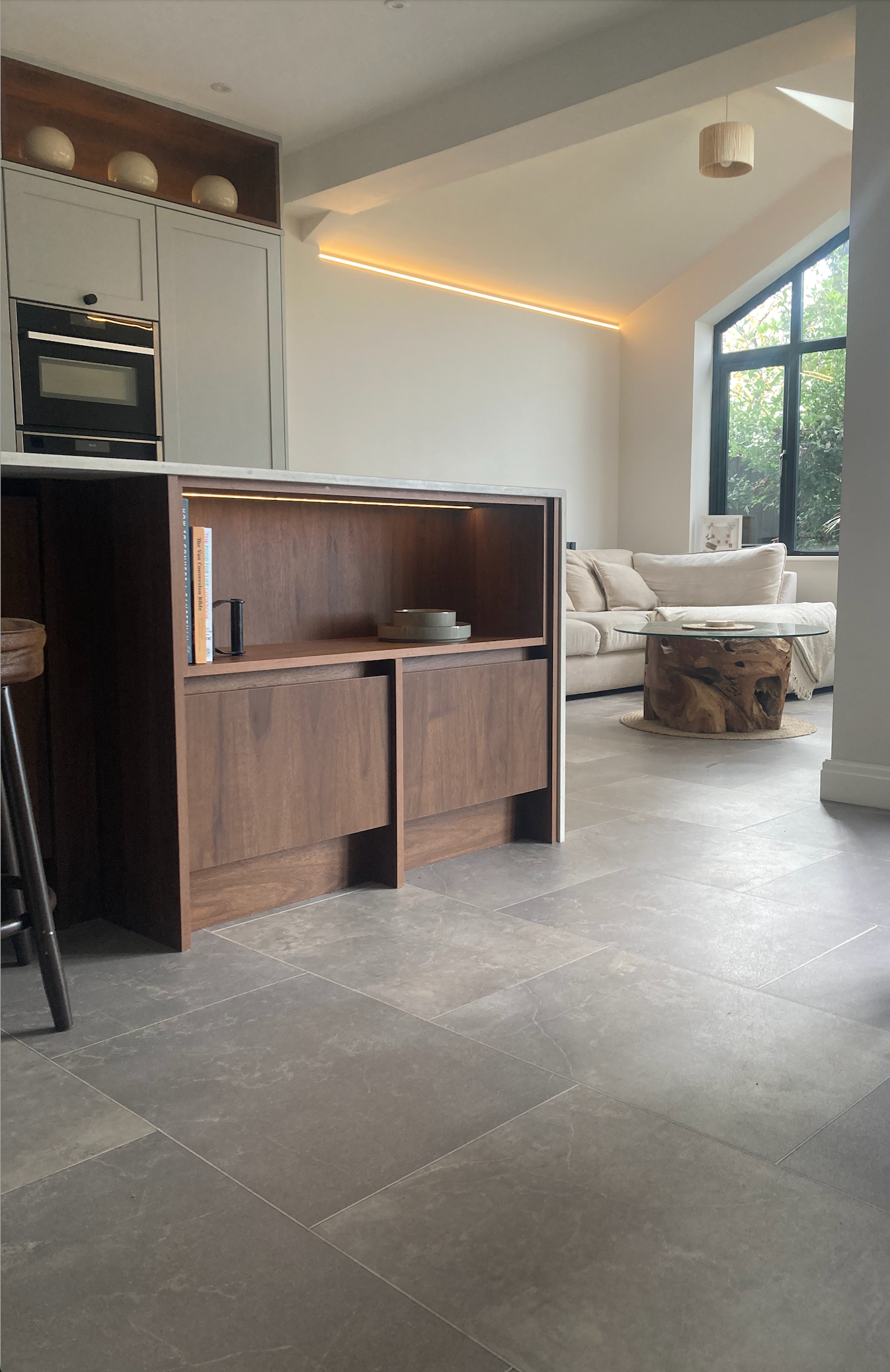 Walnut fitted kitchen island opening onto a living room